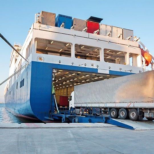 Large cargo truck driving off the dock onto a giant cargo ship